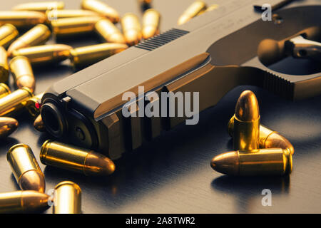 9 mm halbautomatische Pistole mit Full metal jacket Kugeln um auf schwarze Fläche verstreut. Konzeptionelle mockup von Waffengesetz und Kriminalität Stockfoto