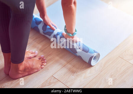 Junge Frau rolling Yoga Matte zu Hause Stockfoto