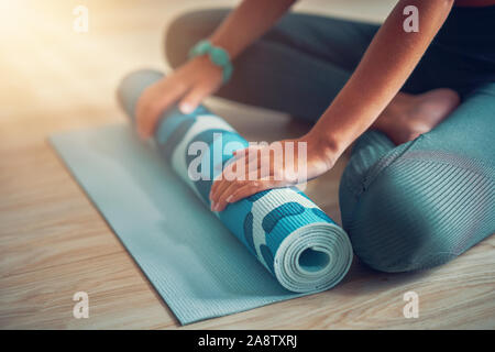 Junge Frau rolling Yoga Matte zu Hause Stockfoto