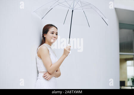Positive junge attraktive asiatische Frau mit transparentem Dach Stockfoto