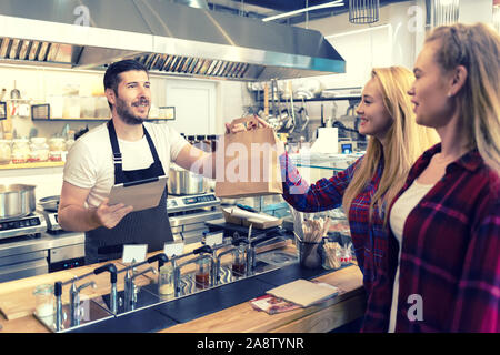 Kellner, das Essen zum Mitnehmen für Kunden an der Theke in der kleinen Familie Restaurant Restaurant Stockfoto