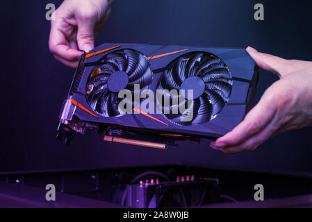 Die Montage einer modernen Grafikkarte Gaming Computer. Leistungsstarke Grafikkarte mit zwei Kühler. Die Hände legen sie die Karte in das Gehäuse des Computers. Stockfoto
