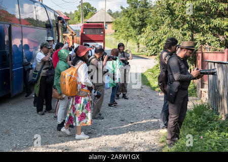 Breb, Maramureș, Rumänien. Eine Gruppe von zumeist chinesischen Touristen, bewaffnet mit großen Kameras aus dem Coach in diesem abgelegenen und ruhigen ländlichen Dorf Stockfoto