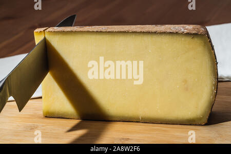 Messer schneiden ein Stück gealtert Comte ein berühmter französischer Käse Stockfoto