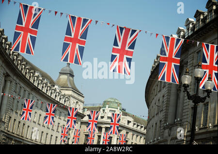 Die Flaggendekoration der British Union Jack hängt über die sich in der Stadt befindlichen Straßen von London, Großbritannien, unter hellblauem Himmel Stockfoto
