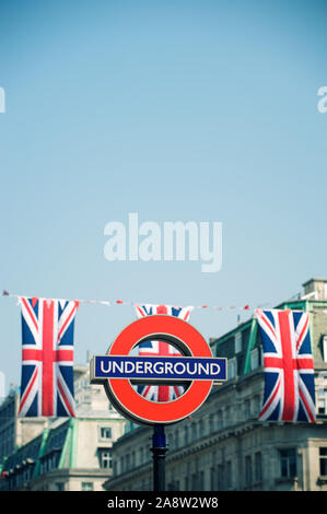 LONDON - 24. MAI 2012: britische Union Jack Flaggen ergänzen die kultige Bar und Kreis roundel von der U-Bahn, ein Design, das 1908 erschien. Stockfoto