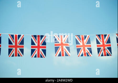 Der britische Union Jack Flagge Bunting hängen draußen in sanften blauen Himmel Stockfoto