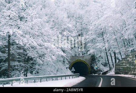 Eingang des Tunnels auf einer verlassenen Straße im Winter bei Schneefall. Stockfoto