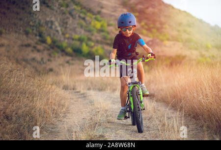 Glückliches Kind Junge von 7 Jahren Spaß im Herbst Park mit dem Fahrrad auf schönen Herbst Tag. Aktives kind Fahrradhelm tragen Stockfoto