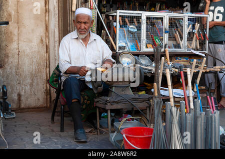 Kashgar, Xinjiang, China - August 16, 2012: ein Mann Schärfen eines Messers an einem Marktstand in einer Straße, in der Stadt Kashgar Xinjiang, China Stockfoto