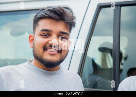Hübscher junger Geschäftsmann entspannt in der Nähe von Auto, Außerhalb Stockfoto