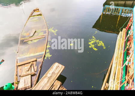 Alte Holz- Boot, Kanu in einem See. Ein rot orange Holz- Boot sitzt auf einem See, Auffüllen mit Wasser Stockfoto