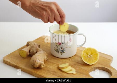 Closeup schuss Ingwer Tee mit Zitrone und Ingwer in der dekorativen Behälter - Woman's Hand mit Ingwer Stockfoto