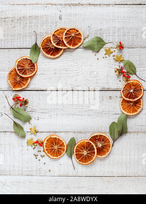 Weihnachtliche Stimmung Kranz aus getrockneten Orangenscheiben, Eukalyptus Blätter, Holz- Sterne und kleine Glocken mit einer Kopie Raum in der Mitte auf einem weißen Holz- Stockfoto