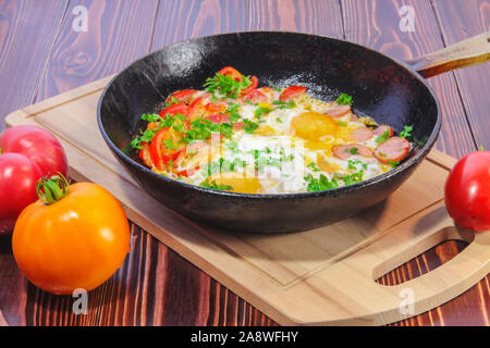 Rührei mit Tomaten, Wurst, Paprika und sprengte mit gehackter Petersilie in einer Pfanne Stockfoto