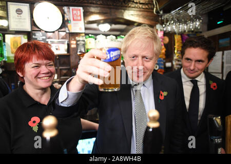 Premierminister Boris Johnson, wirft ein Pint beobachtet von Verteidigungsminister Johnny Mercer (rechts) trifft er sich mit militärischen Veteranen an der Lych Gate Taverne in Wolverhampton. Stockfoto