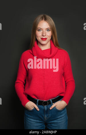 Fröhliche Frau in Rot Pullover auf grauem Hintergrund Stockfoto