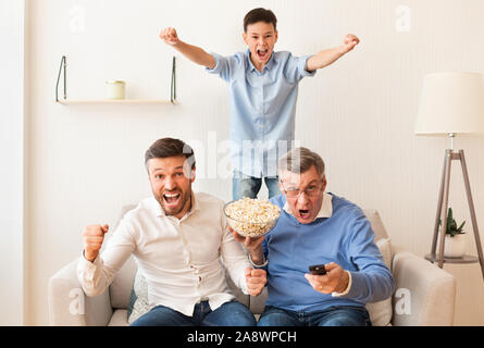 Junge, Vater und Großvater beobachten Fußball Match am TV Indoor Stockfoto
