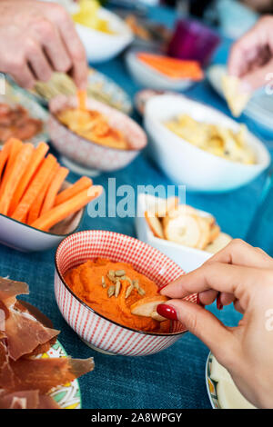 Nahaufnahme der einige Leute einige verschiedene Vorspeisen, wie muhammara, Hummus, Käse oder Serrano Schinken, auf verschiedenen bunten Teller und Bug serviert. Stockfoto