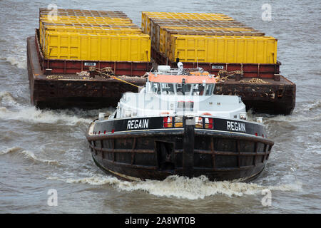 Zwei Binnenschiffe mit gelben Container gesehen von einem schubschiff auf der Themse, London, England, UK gezogen wird geladen. Stockfoto