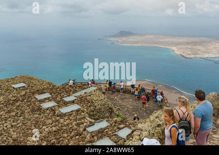 Lanzarote, Kanarische Inseln, Spain-August 31, 2018. Touristen genießen die Aussicht auf die Insel La Graciosa und den Hafen von Caleta del Sebo aus viewpoin Stockfoto