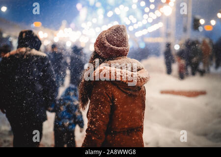 Nicht erkennbare Frau zu Fuß durch Weihnachtsmarkt in Night City Stockfoto