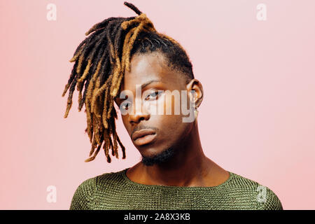 Porträt einer ernsthaften jungen Mann mit Dreadlocks Frisur, isoliert auf Rosa Stockfoto