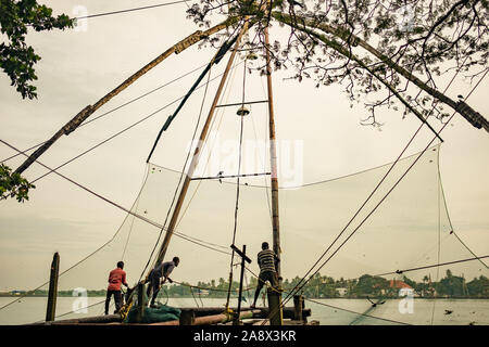 Cochin, Indien - 20. August 2019: Fischer stand auf der traditionellen chinesischen Fischernetze Struktur am frühen Morgen mit warmen natürlichen weiches Licht Stockfoto