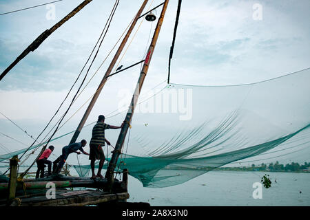 Cochin, Indien - 20. August 2019: indische Fischer stand auf der traditionellen chinesischen Fischernetze Struktur am frühen Morgen mit warmen natürlichen weiches Licht Stockfoto