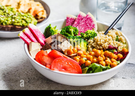 Buddha Schüssel mit Quinoa, frittierte Kichererbsen, geräucherter Tofu und Gemüse in eine weiße Platte. Gesunde vegane Ernährung Konzept. Stockfoto