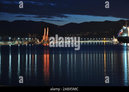 Port mit Kränen und Küste Straße Licht Reflexion auf das Meer Stockfoto