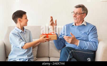 Junge Glückwunsch Opa Geben Geschenk Sitzen auf der Couch Indoor Stockfoto