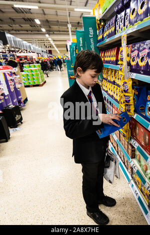 Eine junge schöne Schule Jungen mit ADHS, Autismus, Asperger-syndrom aussieht, durchsucht, wirft einen Blick auf einige Ostereier im lokalen Supermarkt Tesco extra speichern Stockfoto