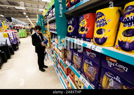 Eine junge schöne Schule Jungen mit ADHS, Autismus, Asperger-syndrom aussieht, durchsucht, wirft einen Blick auf einige Ostereier im lokalen Supermarkt Tesco extra speichern Stockfoto