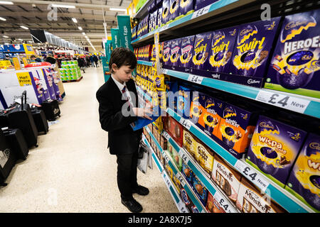 Eine junge schöne Schule Jungen mit ADHS, Autismus, Asperger-syndrom aussieht, durchsucht, wirft einen Blick auf einige Ostereier im lokalen Supermarkt Tesco extra speichern Stockfoto