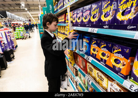 Eine junge schöne Schule Jungen mit ADHS, Autismus, Asperger-syndrom aussieht, durchsucht, wirft einen Blick auf einige Ostereier im lokalen Supermarkt Tesco extra speichern Stockfoto