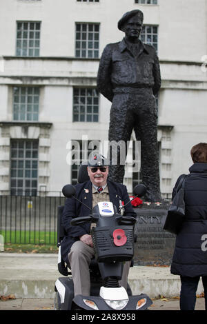 Einem Kriegsveteranen posiert für ein Foto vor einer Statue des Feldmarschalls Bernard 'Monthy" Montgomery, 1. Viscount Montgomery von Alamein, außerhalb des Bundesministerium der Verteidigung, in Whitehall, London, nach einem Armistice Day Service. Stockfoto