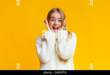 Blonde Mädchen ihre Wangen berühren schockiert, an Kamera suchen Stockfoto