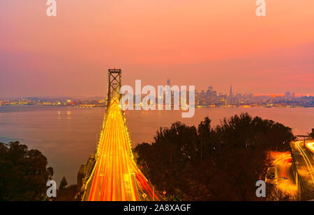 Blick auf die Bay Bridge über die San Francisco Bay mit vielen Autos, die bei Sonnenuntergang in San Francisco vorbeifahren. Stockfoto