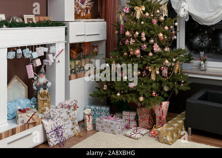 Es ist die Heilige Nacht, die geschmückten Weihnachtsbaum im Wohnzimmer und unten sind die aufgewickelte Weihnachtsgeschenke. Authentisches Bild der eigenen Partei. Stockfoto