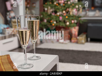 Es ist die Heilige Nacht, die geschmückten Weihnachtsbaum im Wohnzimmer und unten sind die aufgewickelte Weihnachtsgeschenke. 2 Gläser Sekt sind in Stockfoto