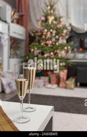 Es ist die Heilige Nacht, die geschmückten Weihnachtsbaum im Wohnzimmer und unten sind die aufgewickelte Weihnachtsgeschenke. 2 Gläser Sekt sind in Stockfoto