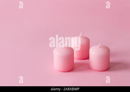Zusammensetzung mit Weihnachten rosa Kerzen auf einem rosa Hintergrund Stockfoto