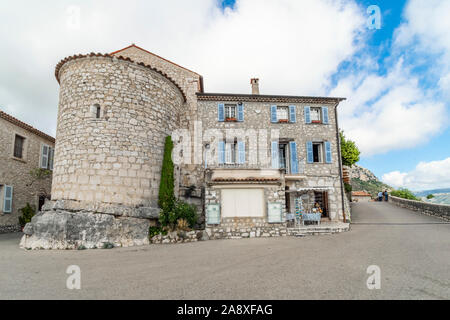 Touristen genießen den Panoramablick auf das Tal von einer Terrasse in der Nähe ein Geschäft im mittelalterlichen Dorf Gourdon in den Alpes Maritimes in Südfrankreich. Stockfoto