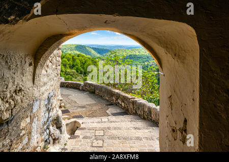 Blick durch einen steinernen Torbogen vom mittelalterlichen Dorf Tourrettes-sur-Loup Frankreich der Alpes-Maritimes Berge des südlichen Franc Stockfoto