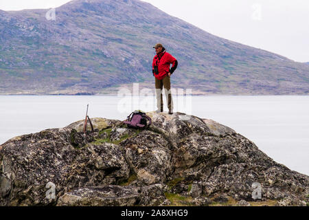 Männliche Tour Leader mit einem Gewehr auf hohen Punkt auf der Suche nach Eisbären standen, die Touristen in Hvalsoy, Qaqortoq, Kujalleq, Grönland schützen Stockfoto