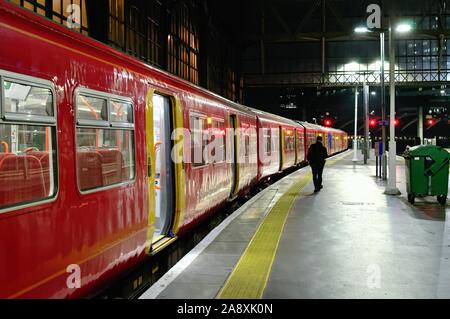 Eine einsame männliche Figur entlang der Plattform in der Waterloo Station über Bord zu einem späten Nacht suburban South Western Railway Bahn, London UK Stockfoto