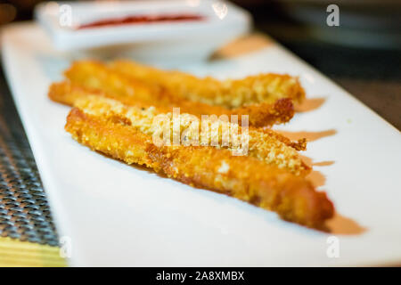 Lange Chicken Nuggets Streifen mit Ketchup auf einem weißen rechteckigen Platte Stockfoto