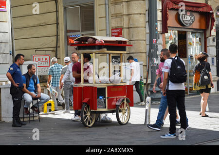 Istanbul, Türkei - 9. September 2019. Einem Straßenhändler verkauft gebratene Kastanien auf der Istiklal Cadessi in Istanbul, Passanten. Stockfoto