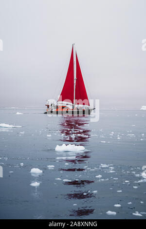 Ein kleines Schiff zwischen Eisbergen. Segelboot Kreuzfahrt unter schwimmende Eisberge in der Diskobucht Gletscher Mitternachtssonne Ilulissat, Grönland. Studium der Ph Stockfoto